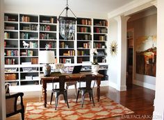 a dining room table and chairs with bookshelves in the background