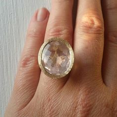 a close up of a person's hand wearing a ring with a stone in it