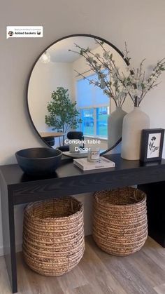 a table with two baskets underneath it and a mirror on the wall in front of it