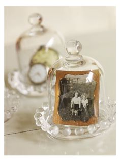 two glass bell jars with an old photo in the top one is holding a clock