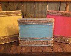 three different colored frames sitting on top of a wooden table next to each other with rope around the edges