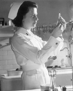 a woman in a white coat is brushing her teeth while standing in the kitchen sink