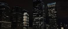 the city skyline is lit up at night, with skyscrapers in the foreground