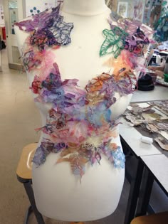 a white mannequin with many different colored leaves on it