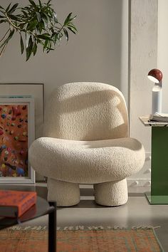 a white chair sitting on top of a floor next to a potted plant in a living room