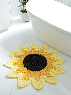 a bath tub sitting next to a yellow and black crocheted doily on the floor