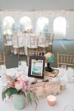 the table is set up for a wedding reception with books and flowers in vases