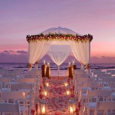 an outdoor wedding setup with candles and flowers on the beach at sunset or sunrise time