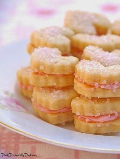 a white plate topped with mini sandwiches on top of a pink and white table cloth