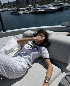 a woman laying on the back of a boat with her hands to her face and eyes closed