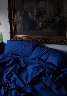 a painting hanging above a bed with blue sheets