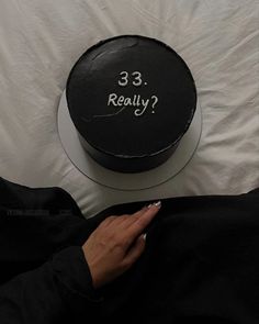 a woman is holding her cell phone in front of a black cake with the words 33 really on it