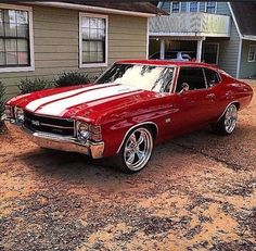 a red and white car parked in front of a house