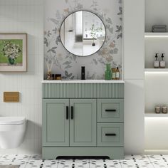 a white toilet sitting next to a green cabinet in a bathroom under a round mirror