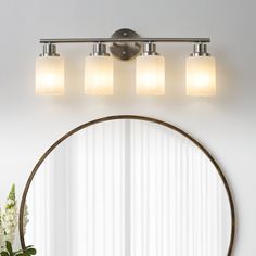 a bathroom vanity with three lights and a round mirror