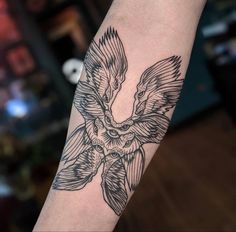 a black and white tattoo on the arm of a person with a bird flying over it