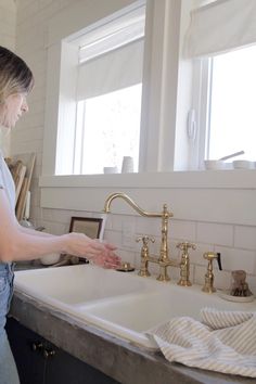 a woman washing her hands in the kitchen sink