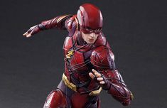 a figurine of the flash is posed on a black surface with grey background