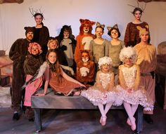 a group of people dressed in animal costumes posing for a photo on a bench with their feet up