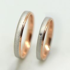 two gold wedding rings with diamonds on each one, set against a plain white background