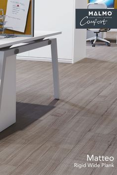 a computer desk with a monitor on top of it next to a chair and table