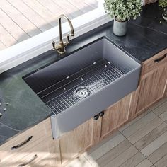 a stainless steel sink in a kitchen with wooden cabinets and counter tops, surrounded by potted plants