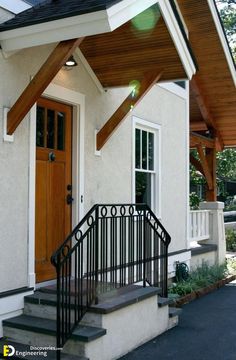 a white house with stairs leading up to the front door and entry way that has a black iron hand rail