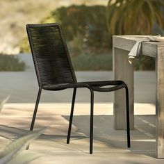 a black chair sitting next to a wooden table on top of a cement slab covered ground