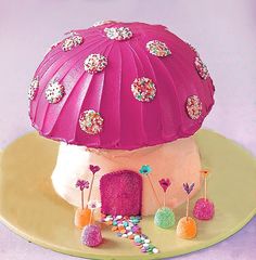 there is a cake that looks like a mushroom house on top of a plate with sprinkles and candies all around it