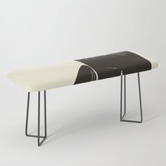 a black and white bench sitting on top of a metal frame stand next to a wall