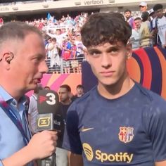 a man talking to an interviewer in front of a crowd at a soccer game