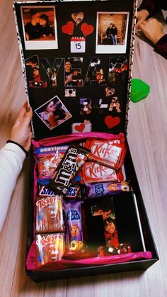 an open suitcase filled with candy and candies on top of a wooden table next to a person's hand