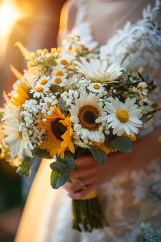 a bride holding a bouquet of sunflowers and daisies