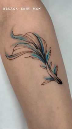 a blue and black feather tattoo on the arm