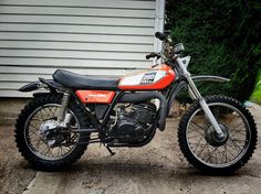 an orange and black dirt bike parked in front of a house