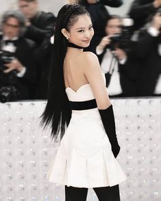 a woman with long black hair standing in front of photographers