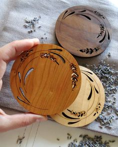 three wooden coasters sitting on top of a table next to lavender flowers and herbs