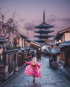 a woman in a pink dress is walking down the street with her arms spread out