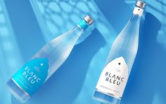 two bottles of blanc bleu water on a blue background with shadows