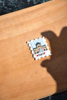 the shadow of a person's hand on top of a wooden table with a stamp