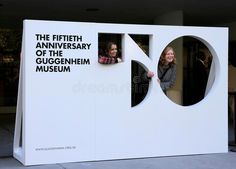 two women are standing in the window of a large white structure that is part of a museum