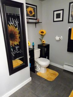 a white toilet sitting in a bathroom next to a yellow rug and pictures on the wall