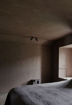 a bedroom with a bed and two lamps on the wall next to it's windows