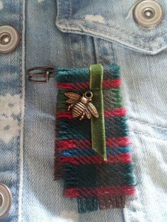 a small cell phone case with a bee on it's side and a green ribbon attached to the pocket