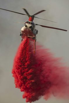 a helicopter dropping fire retardants into the air with it's landing gear