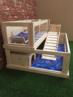 a doll house made out of wood with blue rocks in the floor and red bricks on the wall