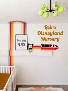 a baby's room with a crib and mickey mouse wall decal