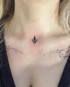 a woman's chest with a small black leaf tattoo on the left side of her chest