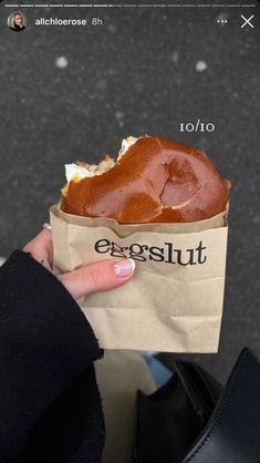 a person holding a piece of food in a paper bag with the word essoult on it