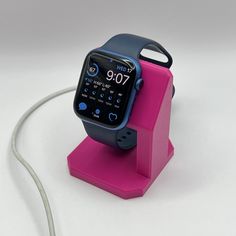 a pink and blue smart watch sitting on top of a charging station